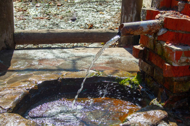 istock Natural spring folded of old bricks and metallic pipe. Clean fresh nature water source from the ground 1154460357
