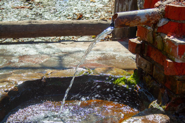 istock Natural spring folded of old bricks and metallic pipe. Clean fresh nature water source from the ground 1154460402