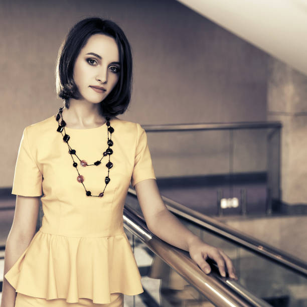 Young fashion business woman in yellow peplum dress at office stock photo