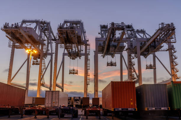 オークランドの港で夕日の空とコンテナクレーンやトラックを出荷。 - port of oakland ストックフォトと画像