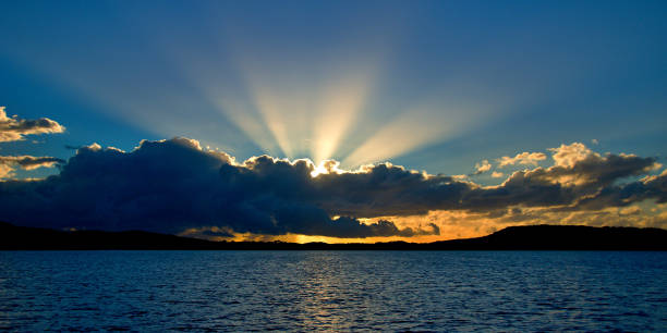 Blue Cumulonimbus cloudy Sunrise Seascape. Australia A stormy radiating crepuscular rays blue,grey and white coloured cumulonimbus cloudy sunrise seascape over sea water with water reflections and ocean sunbeams. Gosford, New South Wales, Australia. gloriole stock pictures, royalty-free photos & images