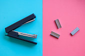 funny stapler and paper clips on blue and pink vivid background