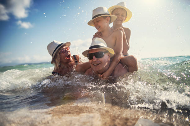 abuelos jugando con nietos en el mar - family beach vacations travel fotografías e imágenes de stock