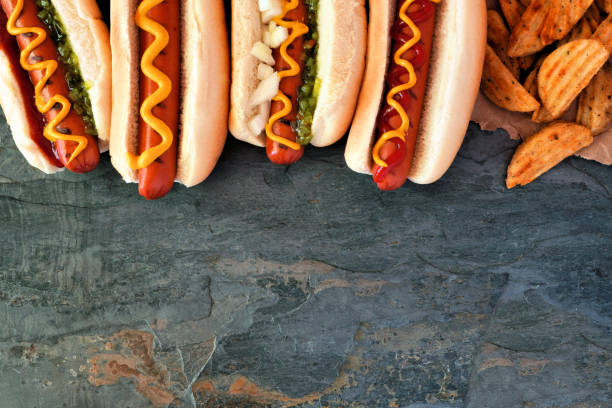 istock Hot dog top border, overhead view on a dark stone background 1154481450