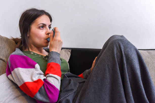 istock Young woman using an asthma inhaler 1154483465