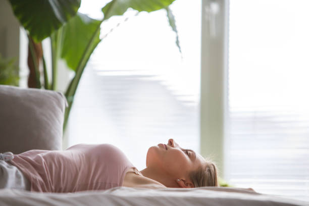 Copy space shot of young woman lying on her back in bed and relaxing in the morning.
