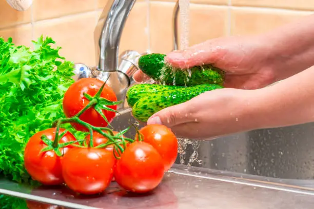 washing cucumbers and vegetables in the kitchen under running water, hands close up