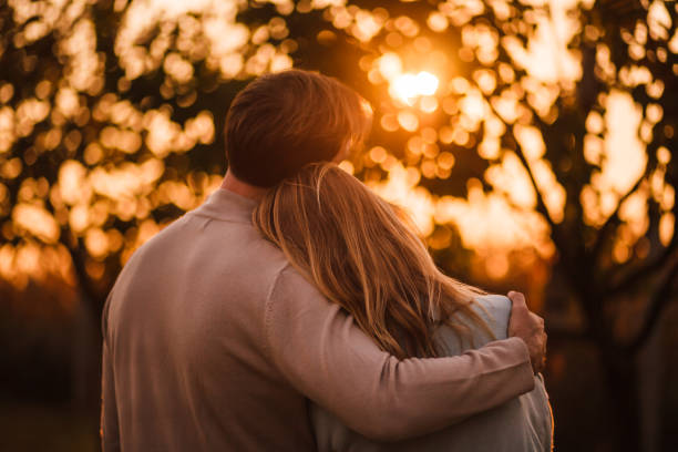 istock Couple hugging and looking at sunset 1154491887