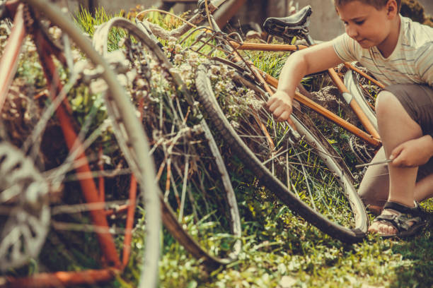 11 year old boy in the backyard near the house on the green grass on the lawn repairing a bicycle