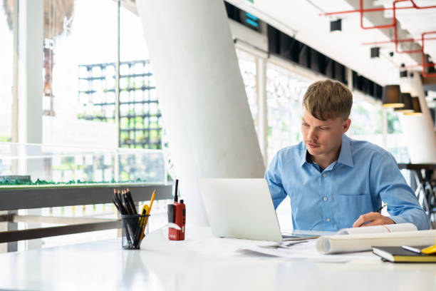 istock Male construction worker working with laptop and blueprints at construction sites office. 1154502374