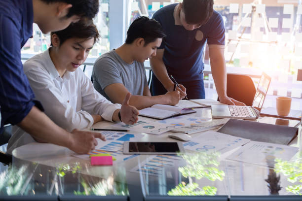 istock Young asian businessmen teamwork brainstorming planning new startup project with chart,graph and business accessories on workplace. selective focus 1154502376