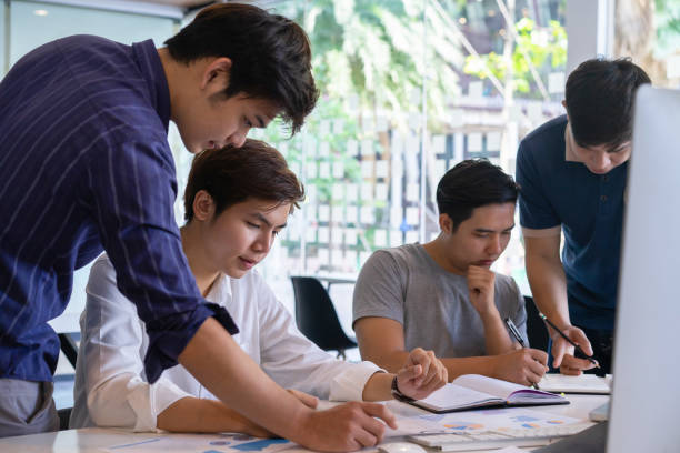 istock Young asian businessmen teamwork brainstorming planning new startup project with chart,graph and business accessories on workplace. 1154504595