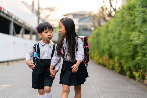 Brother and sister walking home from school together. Tokyo, Japan
