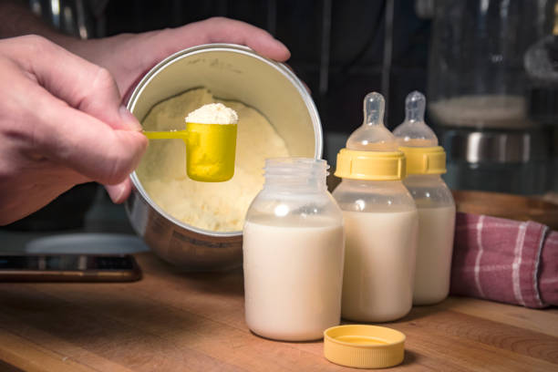 Hand holding scoop of powdered baby formula, ready to mix in bottles measuring the powder for babys nourishment baby formula powder stock pictures, royalty-free photos & images