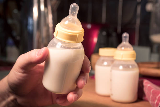 Hand holding baby bottle filled with milk or formula. stock photo