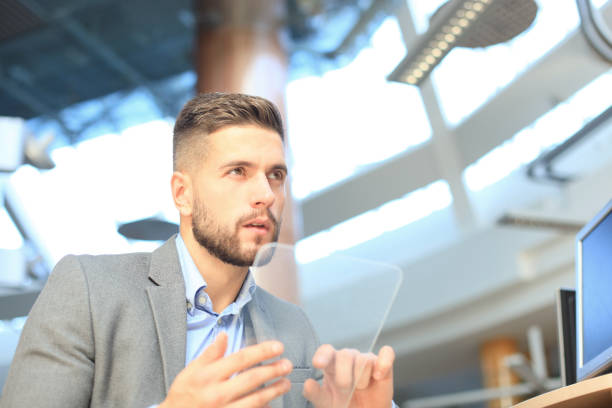 istock Businessman working in office with transparent tablet and laptop. 1154533426