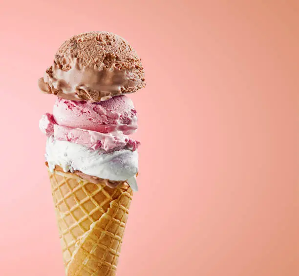 various ice cream balls in waffle cone isolated on pink background