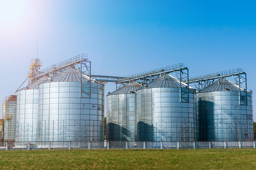 silver silos on agro manufacturing plant for processing drying cleaning and storage of agricultural products, flour, cereals and grain