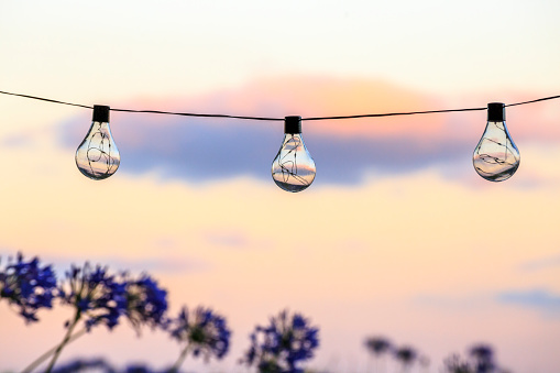 Sunset refracts through a string of lightbulbs in Whangamata