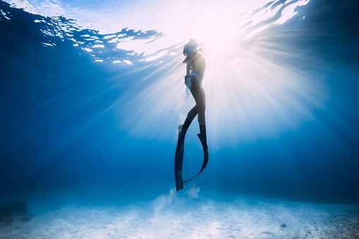 Chica Freediver en bikini sobre mar arenoso con aletas. photo