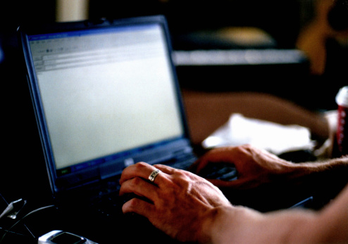 Close-up of hands on a laptop writing an email.