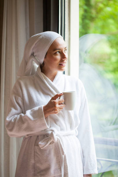 istock Beautiful woman in bathrobe drinking coffee 1154555808