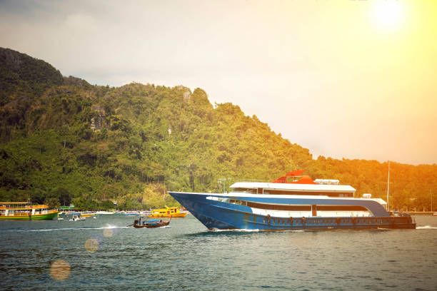 istock Blue and white passenger ship sailing to destination point. Dock with another ships and mountain on background. 1154556900