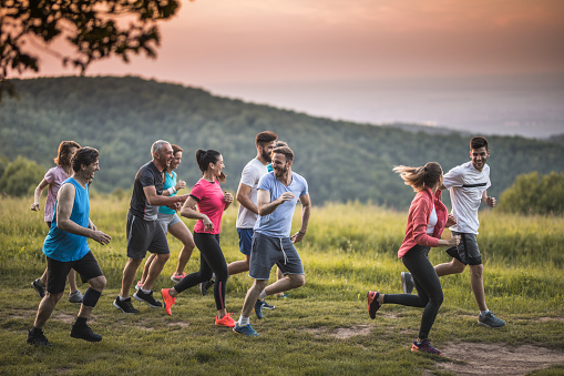 Group of happy athletes having fun while running a race in nature. Copy space.