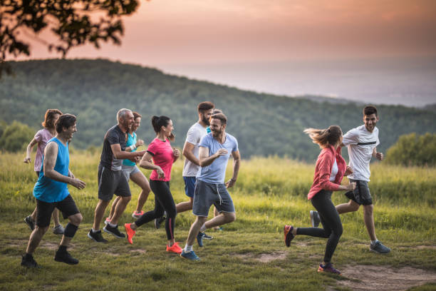 Large group of happy athletic people running through nature. Group of happy athletes having fun while running a race in nature. Copy space. distance running stock pictures, royalty-free photos & images