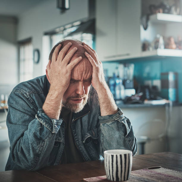 istock Troubled middle-aged man clutches his head in despair 1154560223