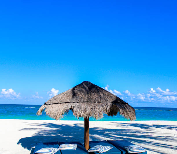 This is a scene from a beach in Tulum Mexico.  Caught this relaxing show with a thatched umbrella and two chairs looking out toward the Caribbean sea.