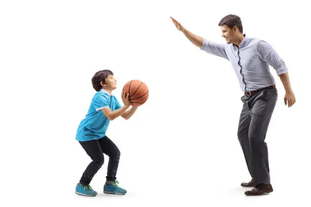 Photo of Boy throwing a basketball and playing with his father