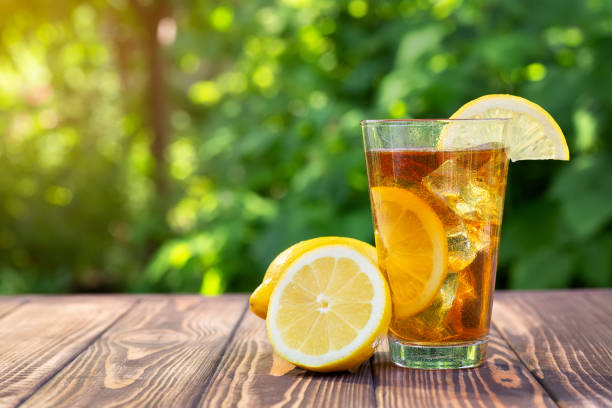 glass of ice tea on wooden table glass of ice tea with lemon on wooden table outdoors iced tea stock pictures, royalty-free photos & images