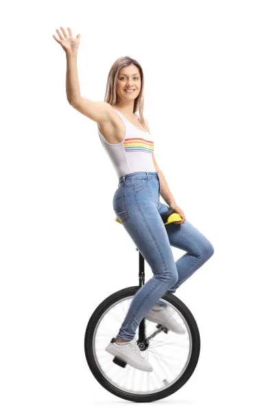 Young beautiful woman riding a unicycle and waving isolated on white background