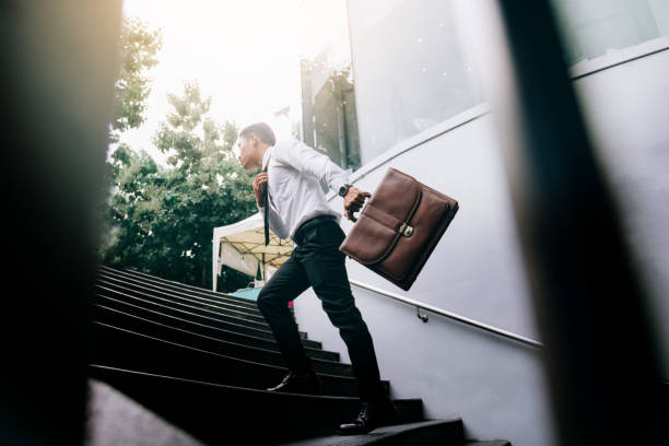 istock Businessman walking up on stairs and holding briefcase. 1154563497