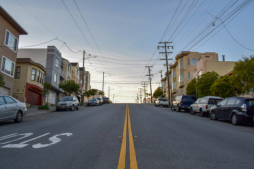 View of a crooked street in a residential neighborhood at sunset in San Francisco, CA. Photo taken in January 2019.