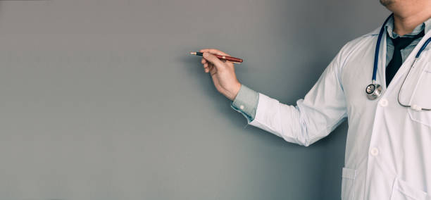 istock Doctor pointing pen at wall background with copy space. 1154564024