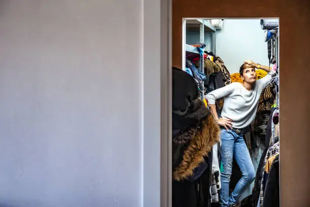 Annoyed Adult Woman Leaning on a shelf in her Closet