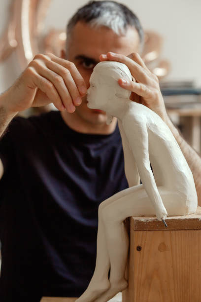 sculptor at work sculptor making the girl's figurine of white clay clay sculpture stock pictures, royalty-free photos & images