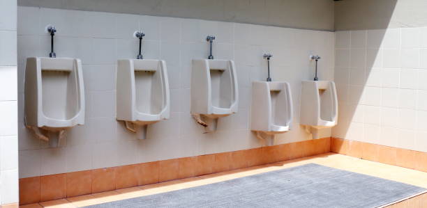 toilette extérieure vieille couleur orange, la toilette de l'homme avec la vue de toilette par des urinoirs - urinal public restroom male toilet in a row photos et images de collection
