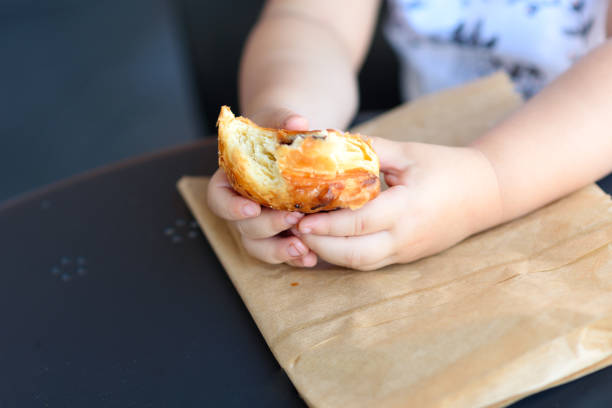 istock Close up kid hands holding croissant. 1154573176