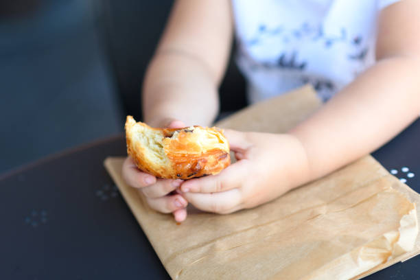 istock Close up kid hands holding croissant. 1154573182