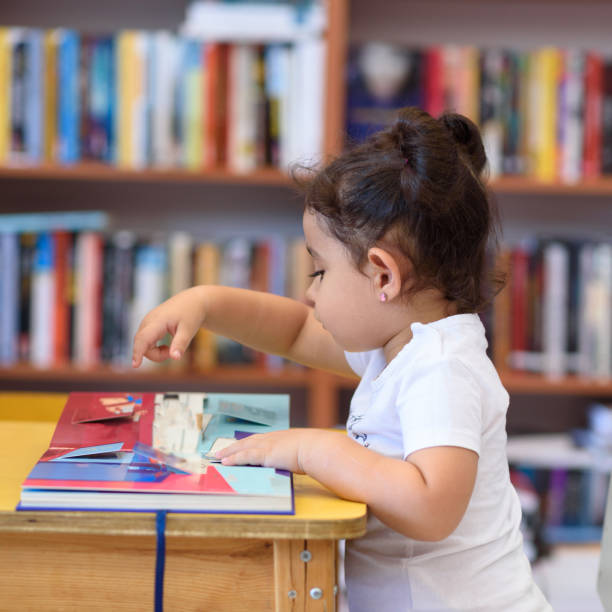 istock Happy child little girl reading a book. 1154573185