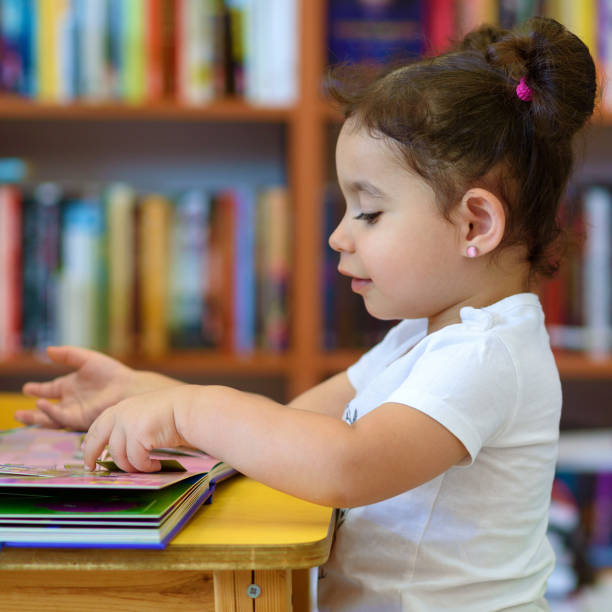 istock Happy child little girl reading a book. 1154573193