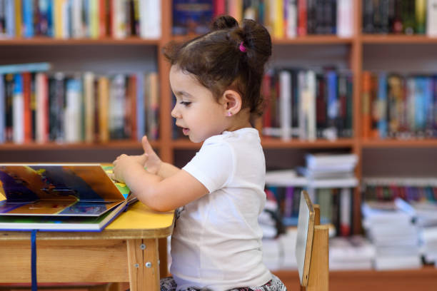 istock Happy child little girl reading a book. 1154573205
