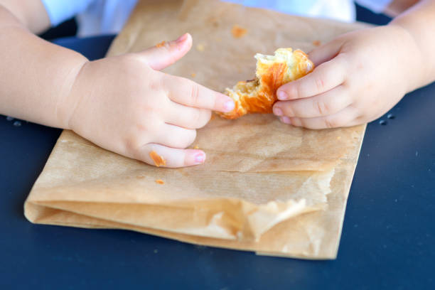 istock Close up kid hands holding croissant. 1154573215