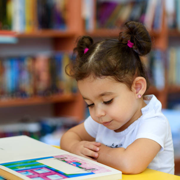 istock Happy child little girl reading a book. 1154573216