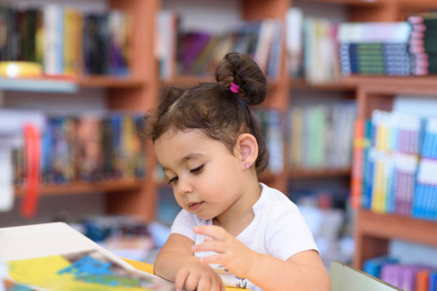 istock Happy child little girl reading a book. 1154573219