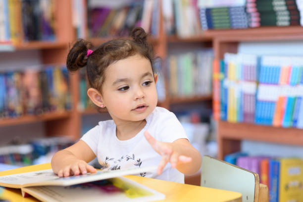 istock Happy child little girl reading a book. 1154573221
