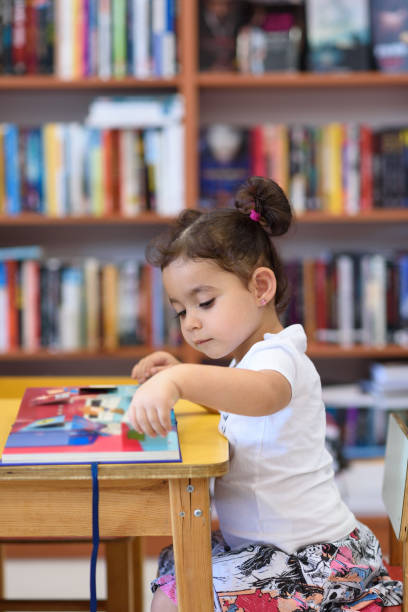 istock Happy child little girl reading a book. 1154573224